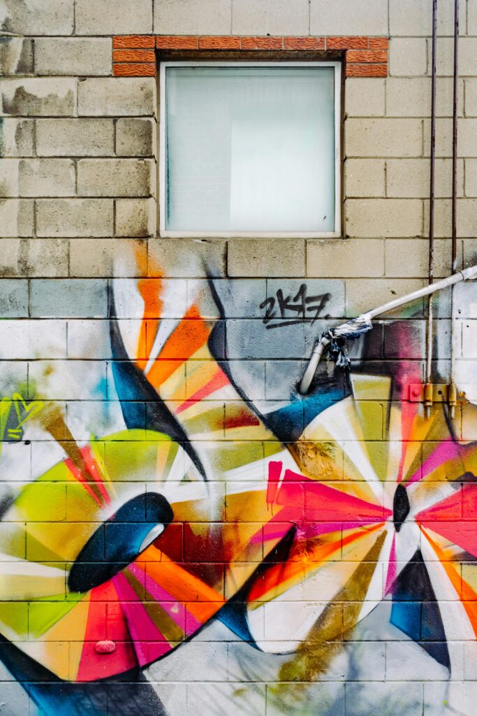 Colorful graffiti art on a brick wall with a window, showcasing urban creativity.